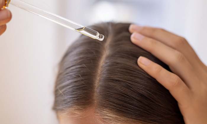 Mujer aplicándose aceite en su cabello