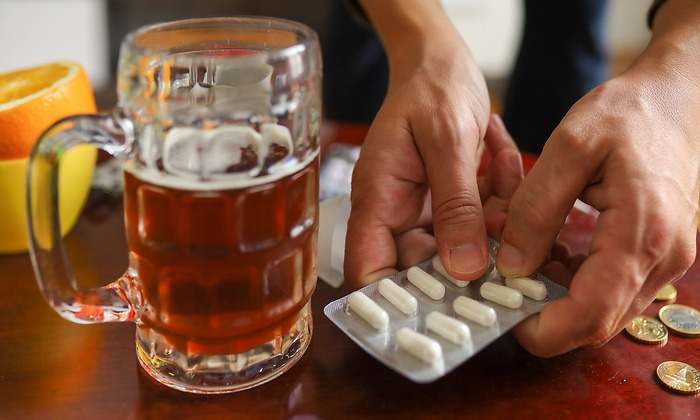 Medicamentos y una jarra de cerveza sobre una mesa de madera