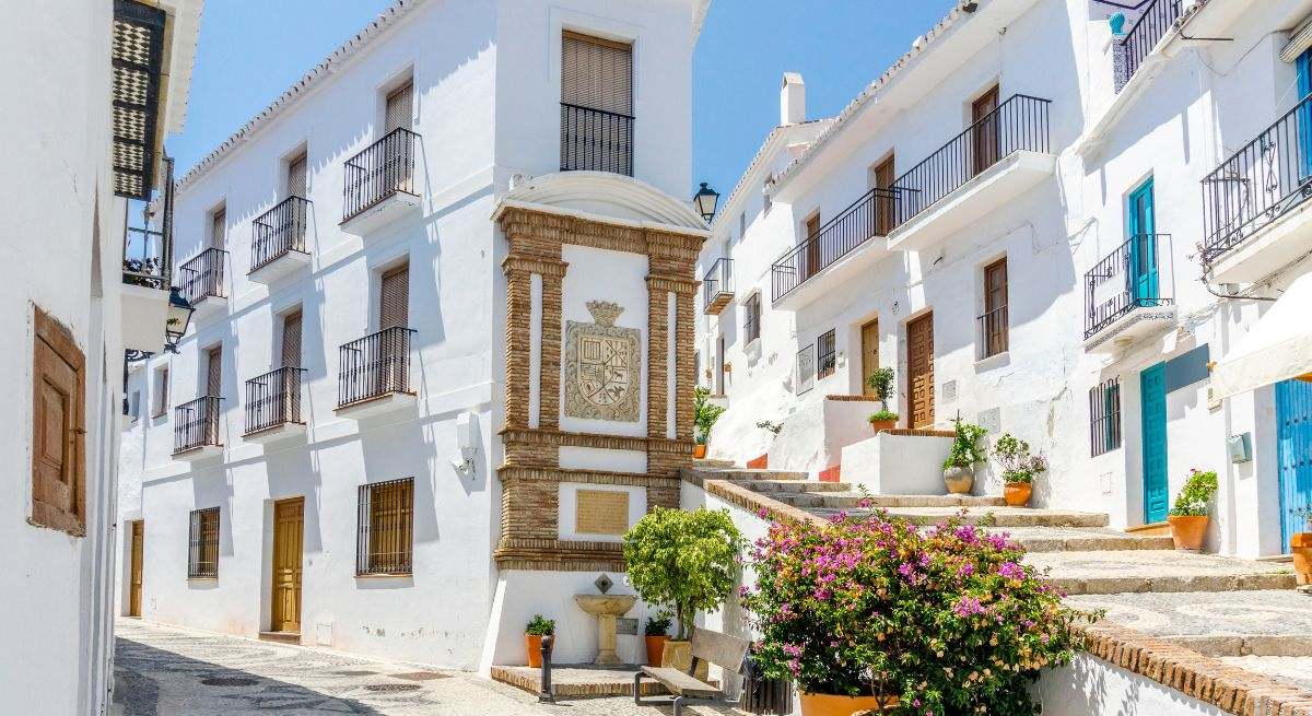 Calle con fachadas blancas y rosetones en medio