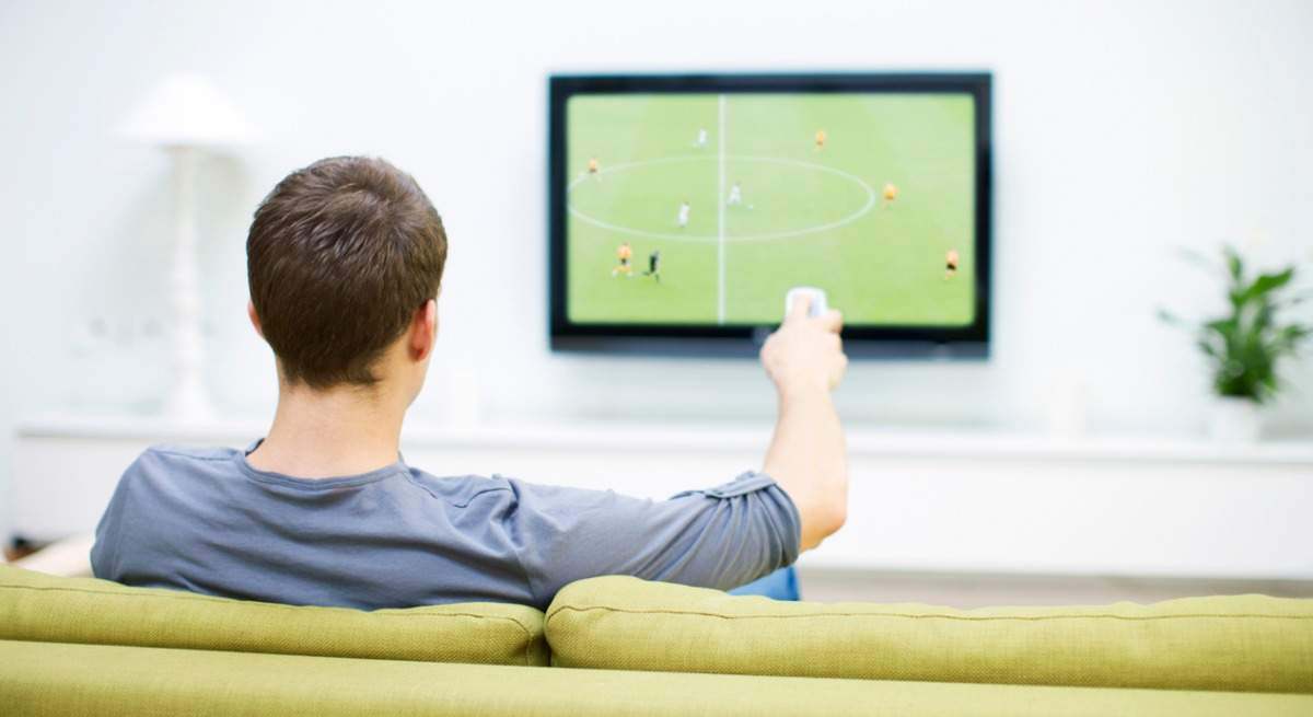 un hombre viendo el fútbol por televisión