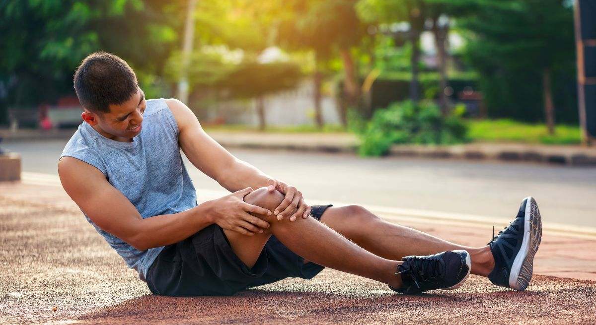 Un hombre de mediana edad se duele de la rodilla en un parque