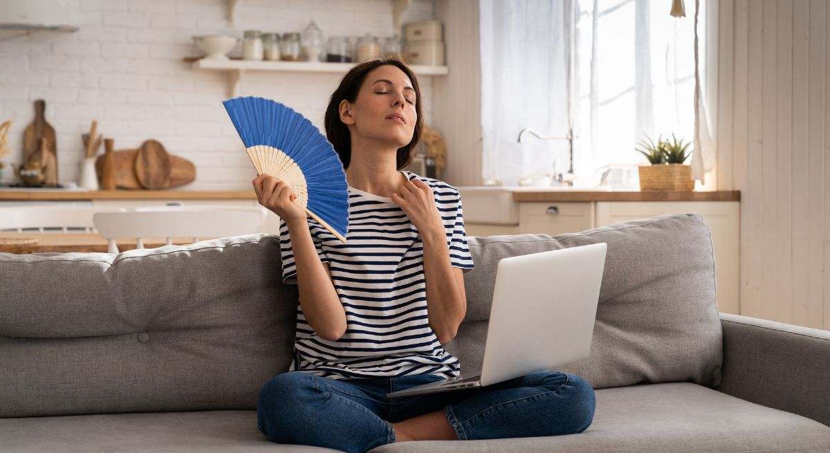 Mujer abanicándose porque sufre por el calor del verano
