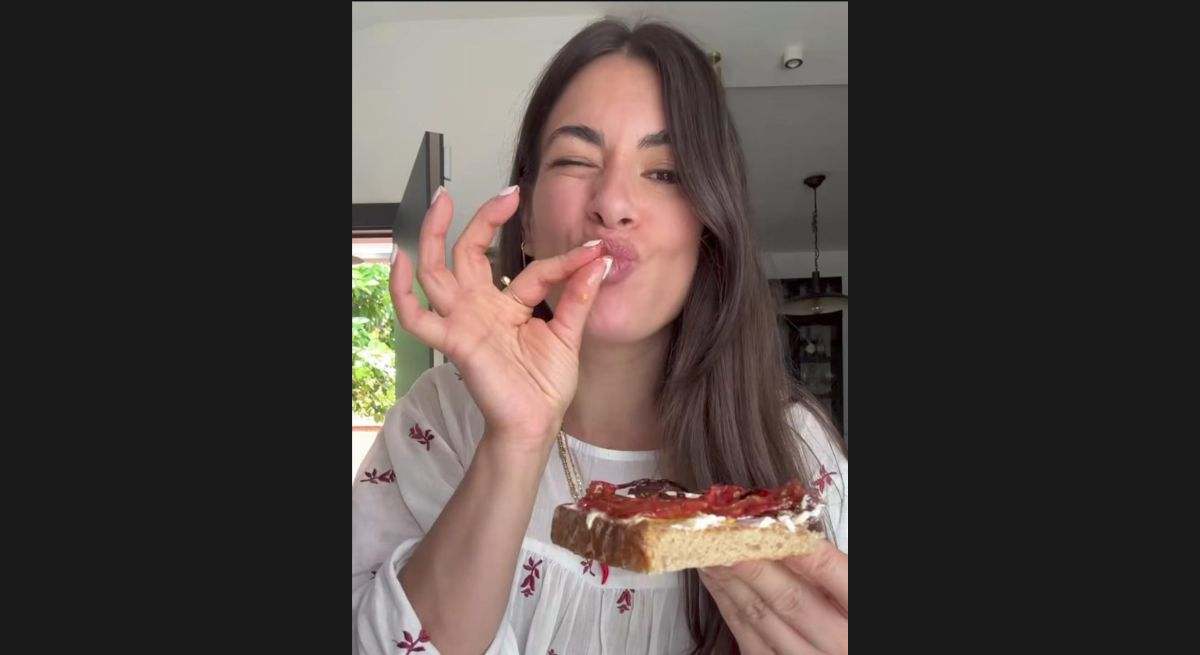 Chica comiendo una tostada de tomates al horno y queso fresco