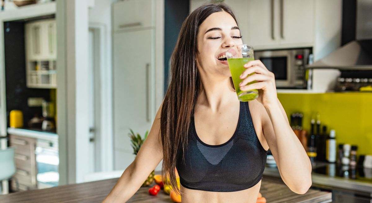Chica tomándose una bebida verde en una cocina moderna 