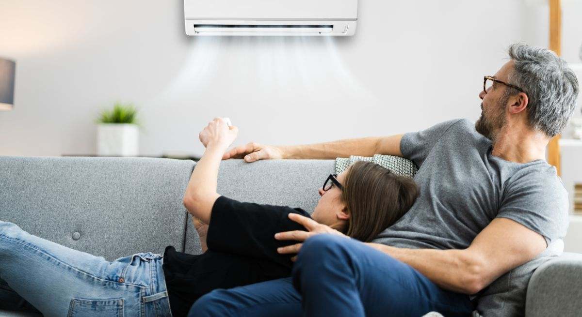 Pareja con el aire acondicionado tumbados en el sofá