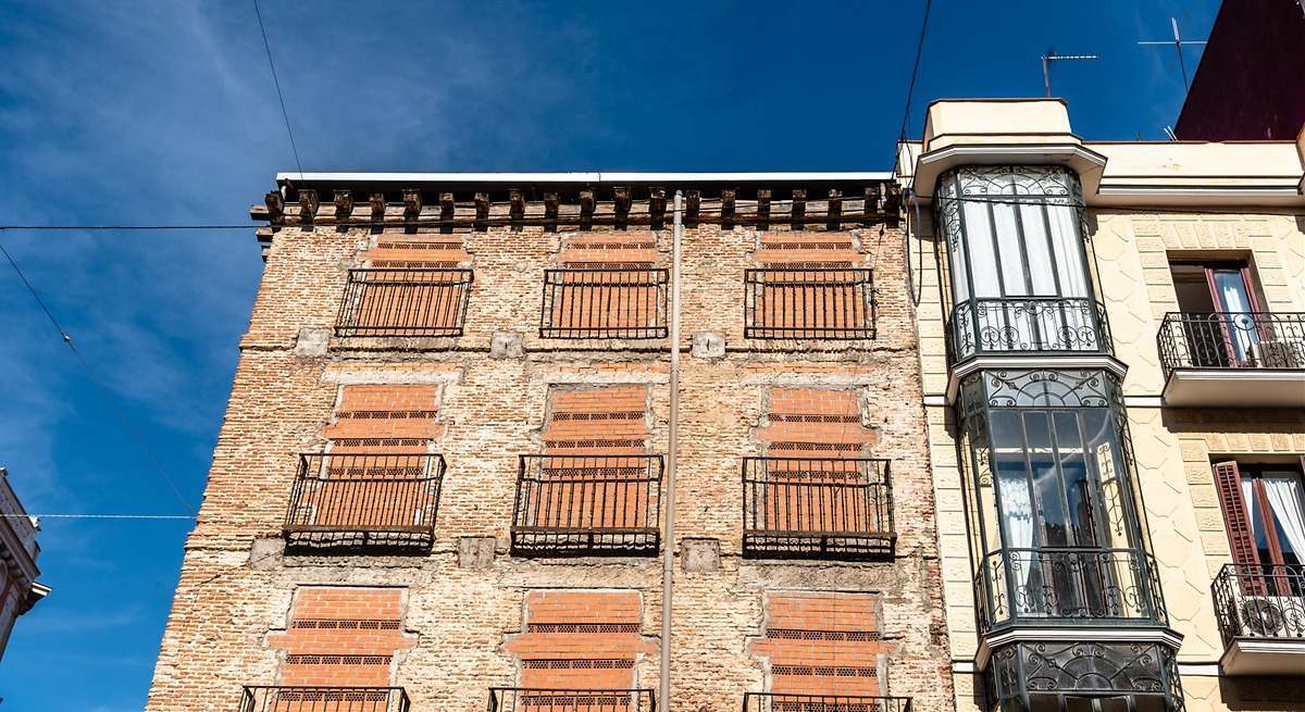 Antiguo edificio residencial con ventanas tapiadas para evitar la entrada de okupas | iStock