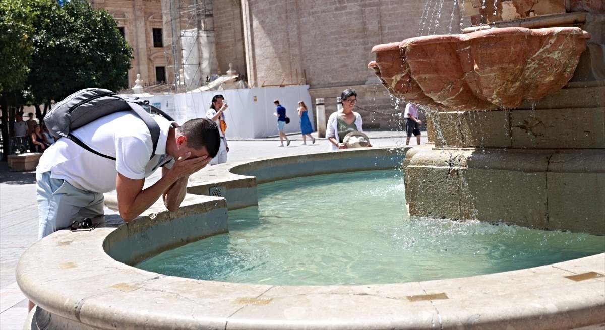 Una persona se refresca en una fuente de Sevilla / EP