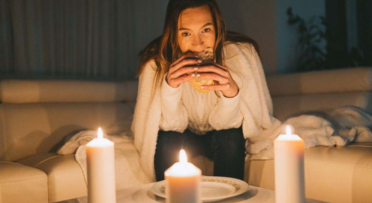 Una mujer cena en su casa con tres velas tras el apagón eléctrico en España