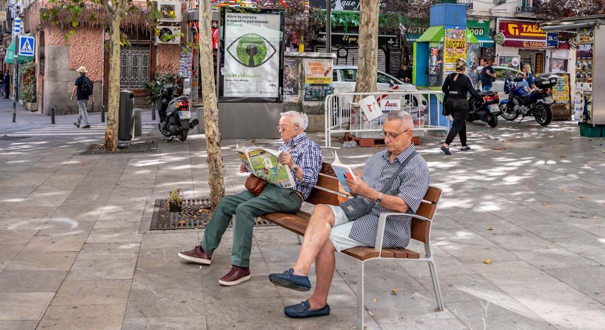 Dos jubilados leyendo en un banco en la calle. Foto: iStock