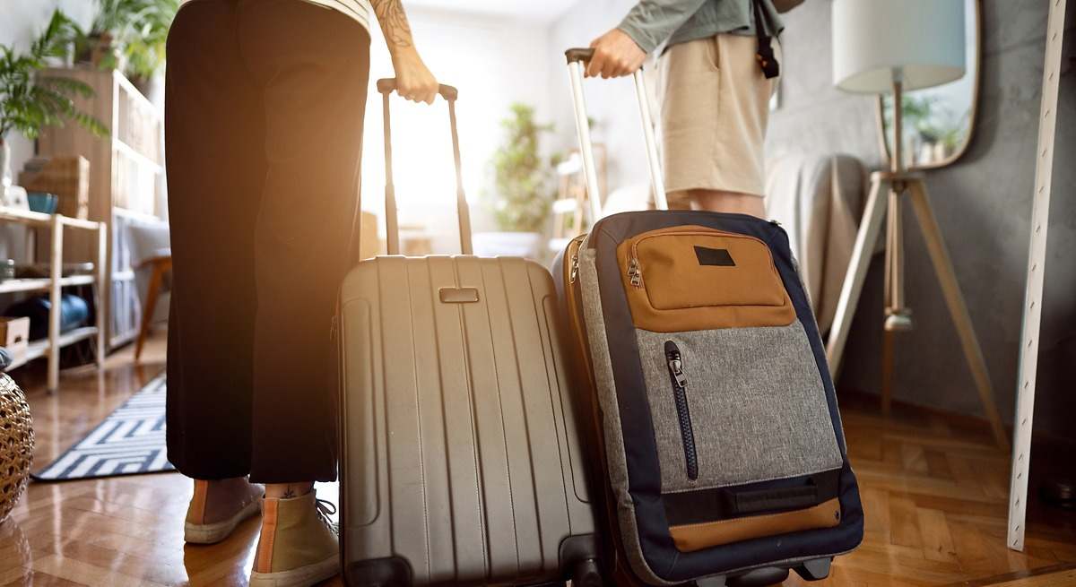 Dos personas con maletas en un apartamento. iStock