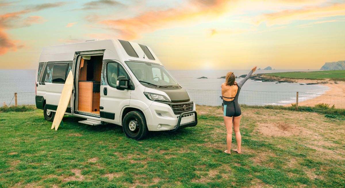 Joven poniéndose su traje de neopreno para surfear junto a su autocaravana