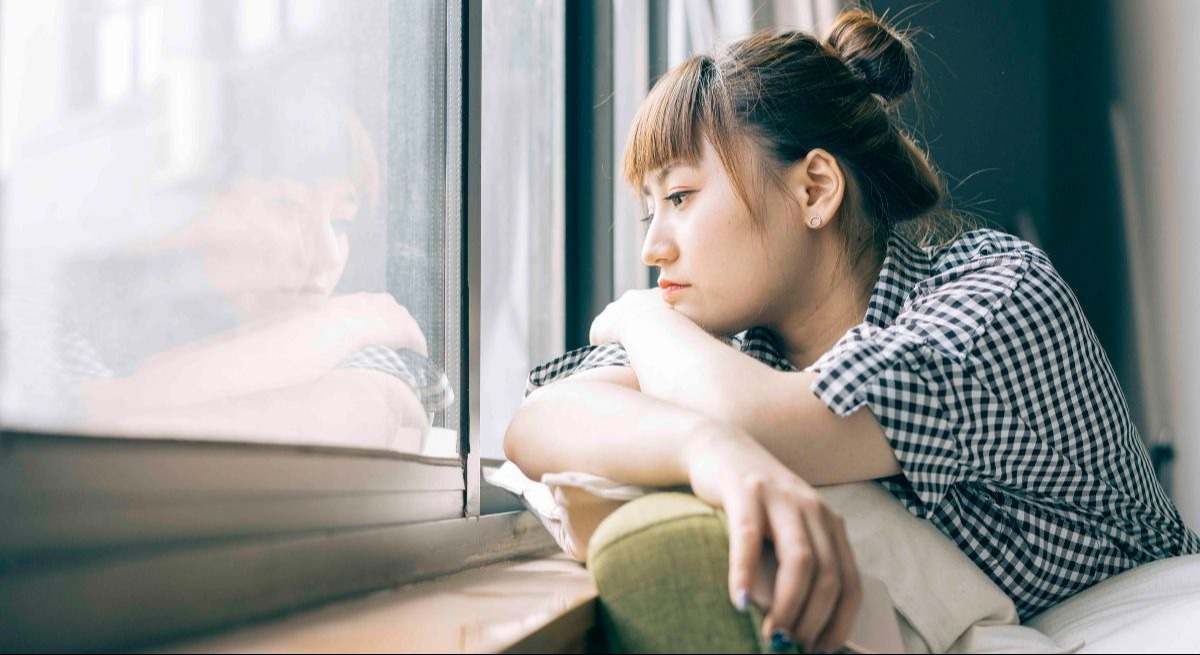 Mujer sola mirando a través de una ventana