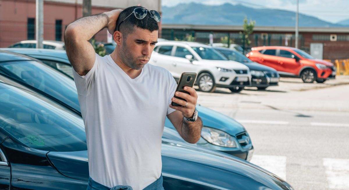 Hombre comprando coche mirando el teléfono móvil