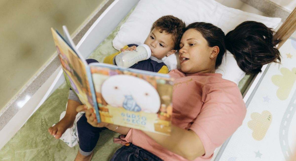 Madre e hijo leyendo un libro en la cama