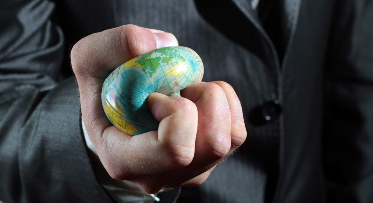 capitalismo-globalizacion-globo-terraqueo-pelota-aplastado-mano-dreamstime-1200x655.jpg