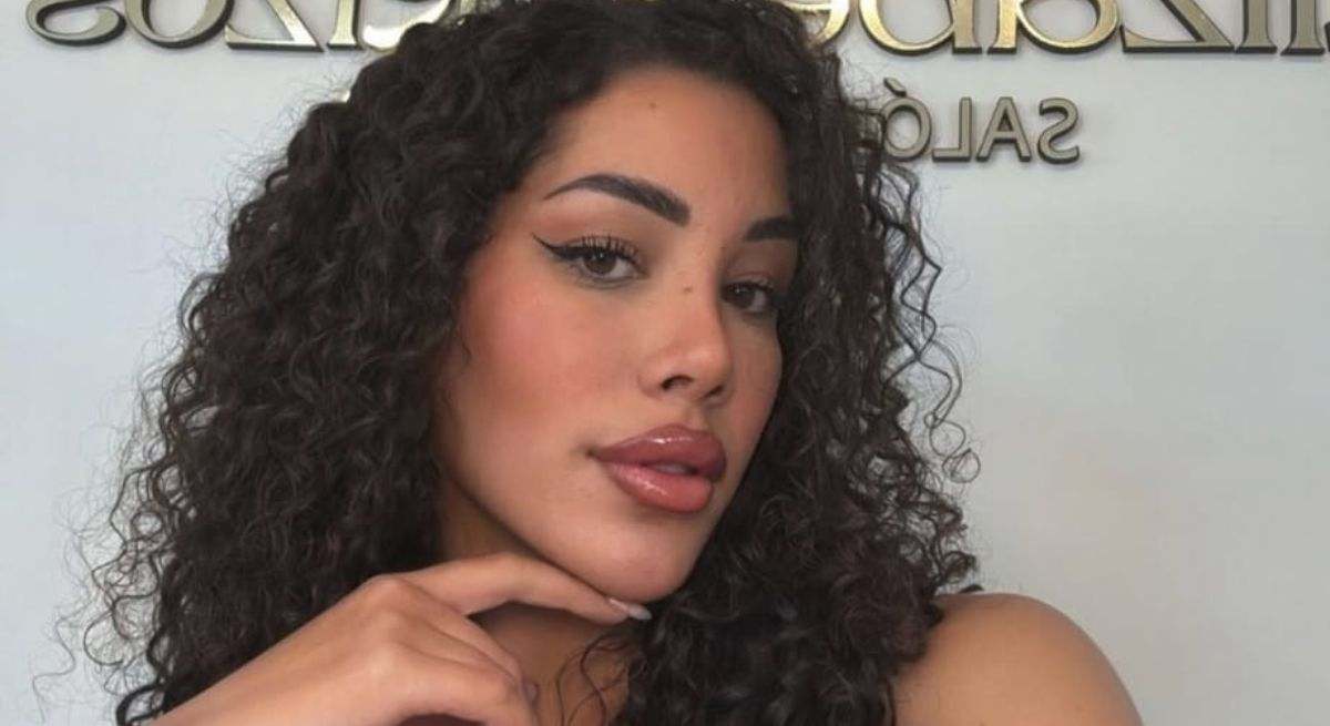 La concursante con pelo rizado posando con un fondo blanco