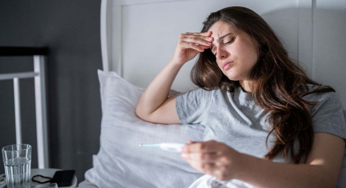 Mujer con fiebre en la cama