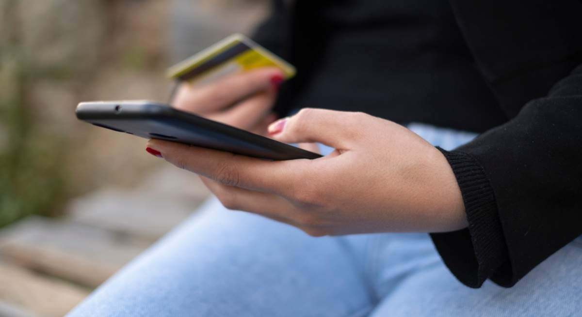 un usuario sujeta un teléfono y una tarjeta de crédito