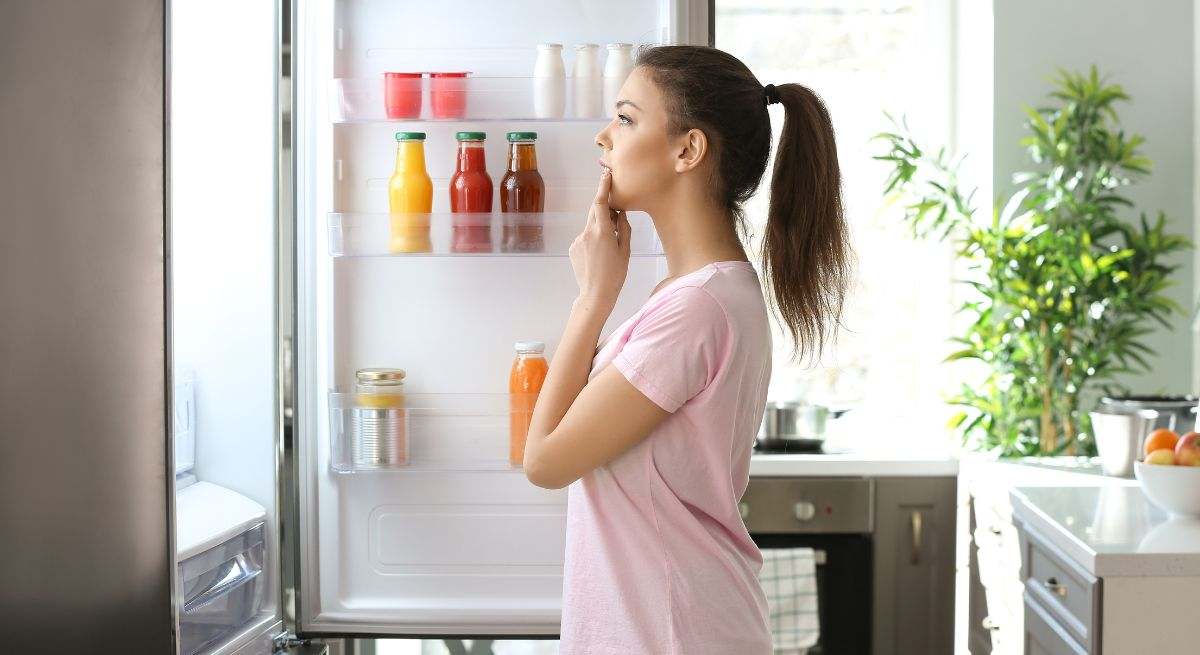 Chica abriendo la nevera para coger algo de comer