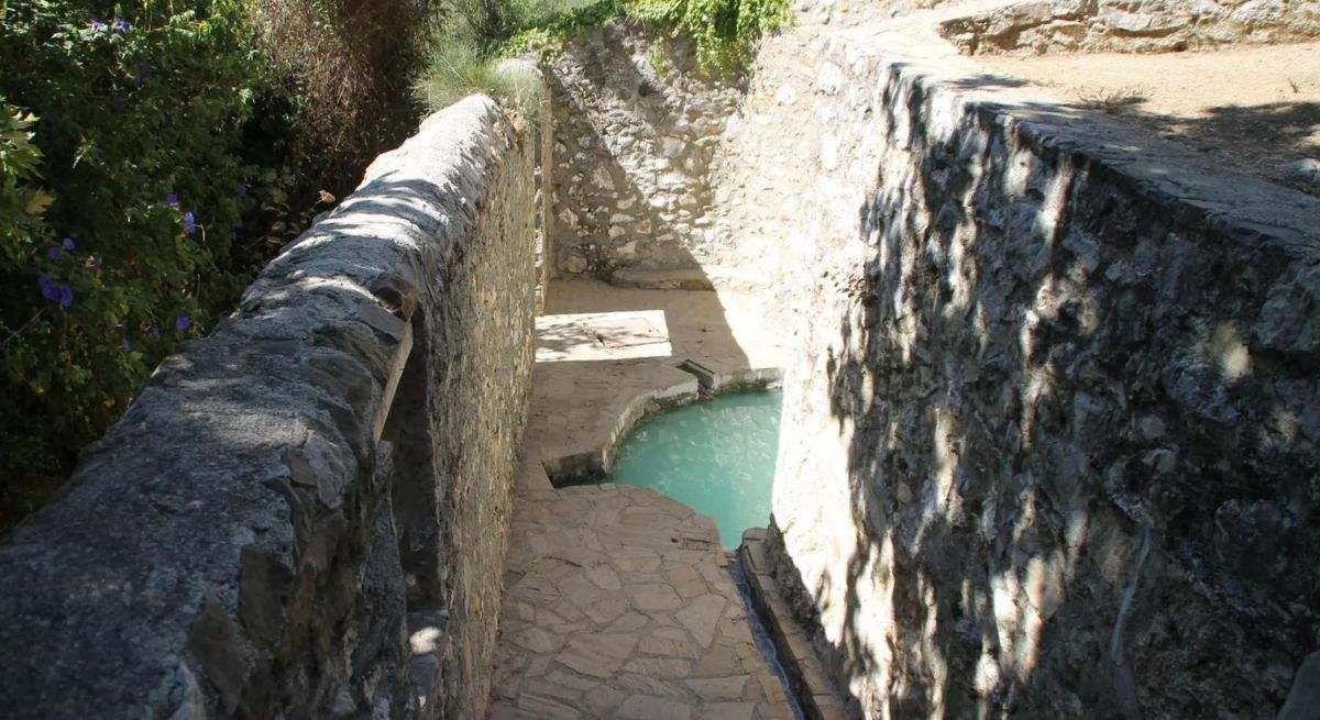 Zona de aguas termales tras un muro de piedra
