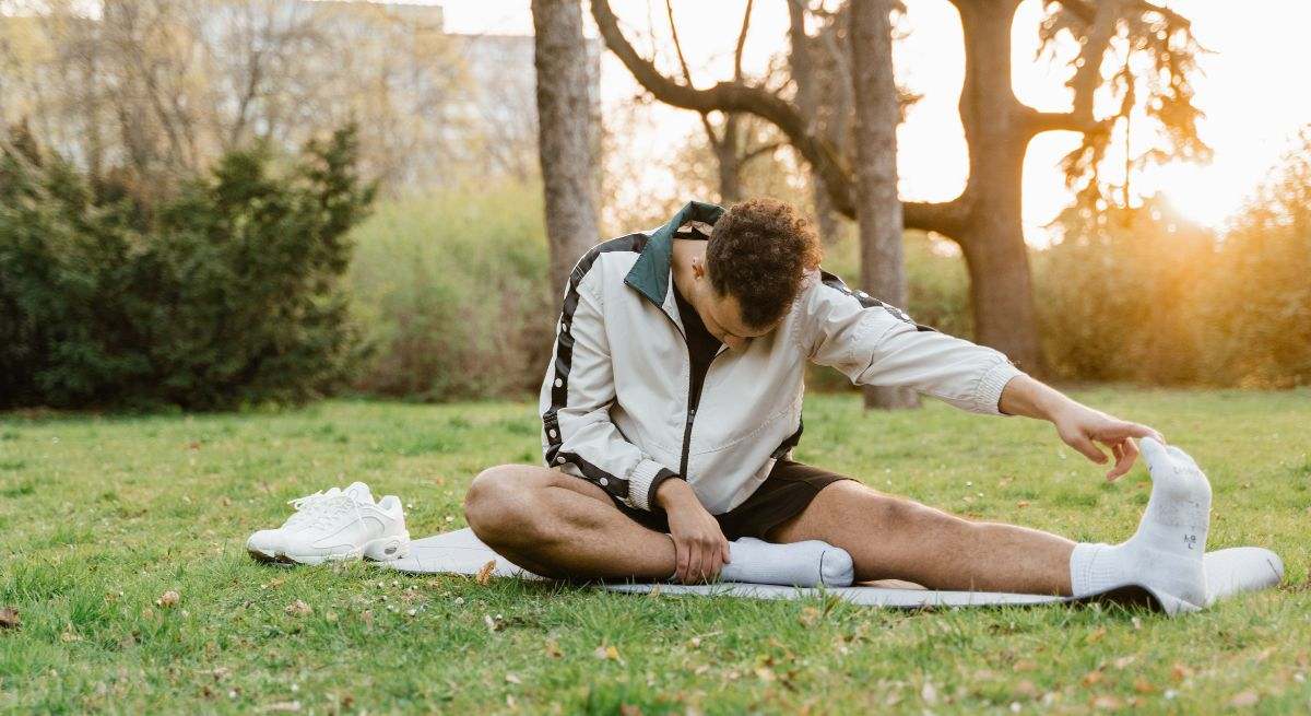 Joven estirando en el parque
