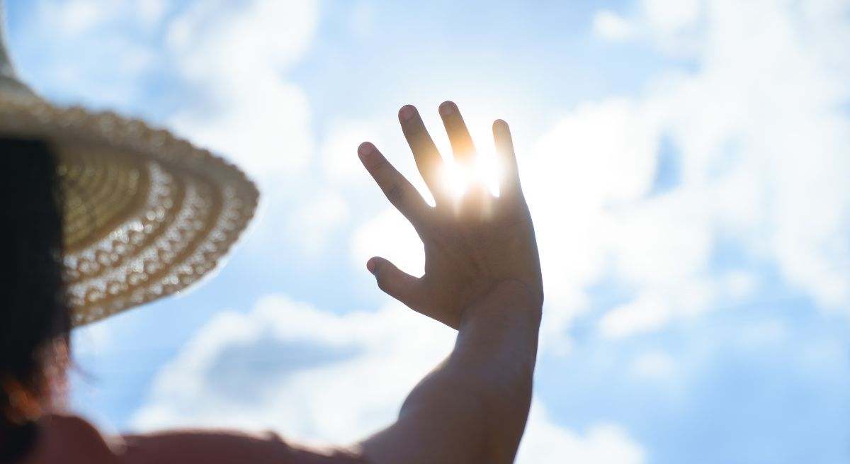 Una mujer tapa el sol con su mano