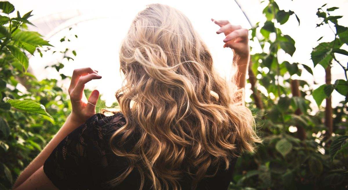 Chica rubia de espaldas con cabello ondulado 