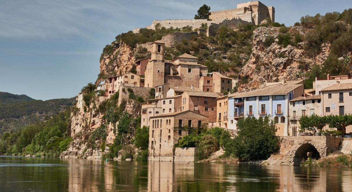 El pueblo de Miravet con casas incrustadas en su montaña y el río abajo