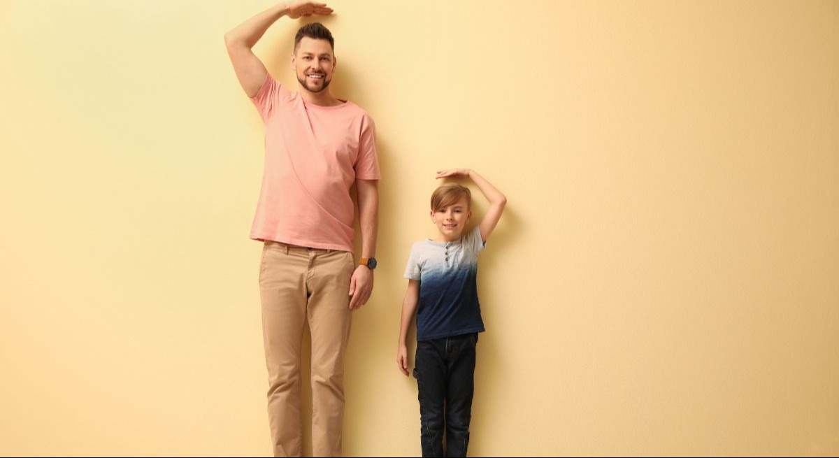 Padre e hijo comparando su altura en una pared