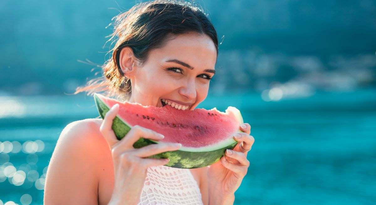 Una mujer come sandía en la piscina