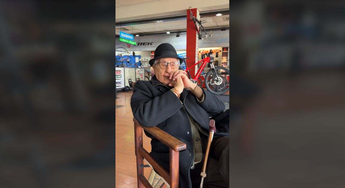 Entrevista al dueño de una tienda de bicicletas con sombrero negro y bastón sentado en una silla de madera