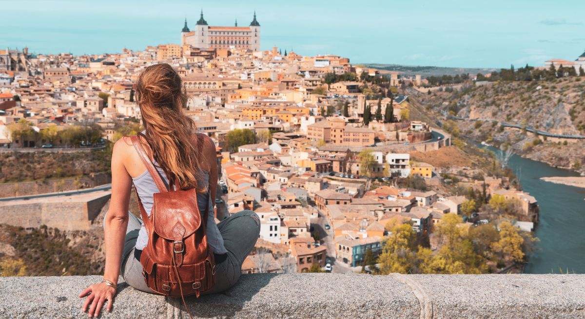 Chica con mochila roja mirando al horizonte de Toledo