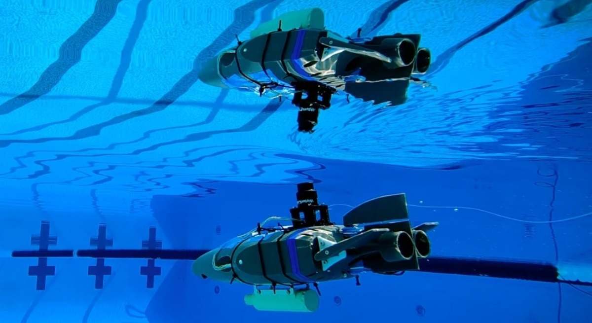 Un prototipo de robot diseñado para explorar los océanos subterráneos de las lunas heladas se refleja en la superficie del agua durante una prueba en una piscina en Caltech en septiembre