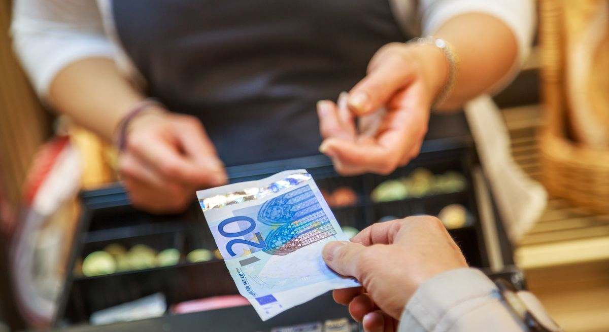 Mujer pagando con un billete de 20 euros a una cajera
