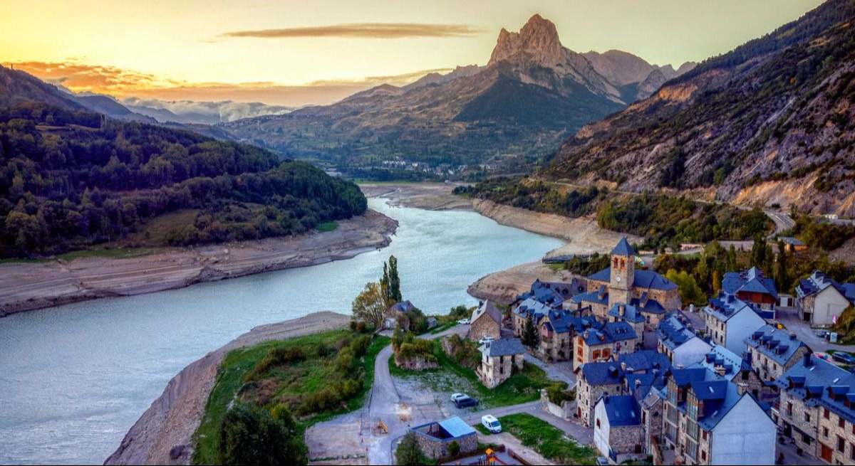 Pueblo muy similar a Arendelle con casas de tejado a dos un lago y montañas imponentes