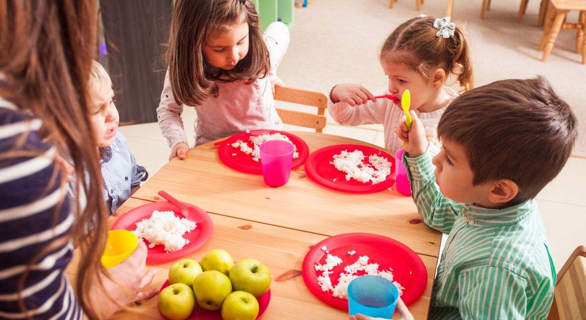 Varios niños comen su plato principal con una sonrisa