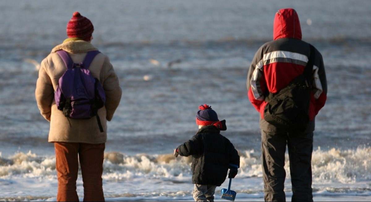 Dos personas con un niño delante de la playa