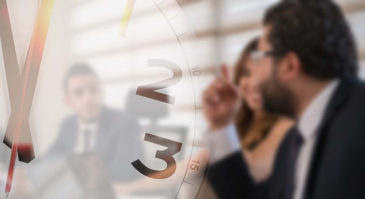 Trabajadores en una reunión bajo un reloj