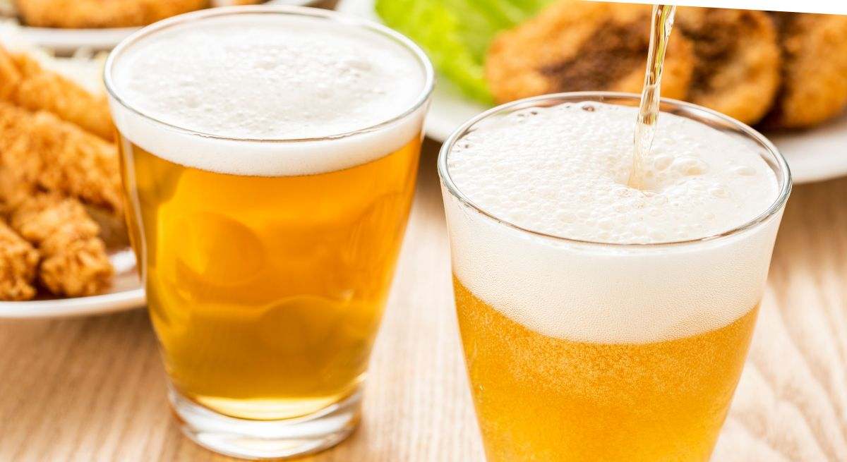 Cervezas sobre una mesa con comida de fondo
