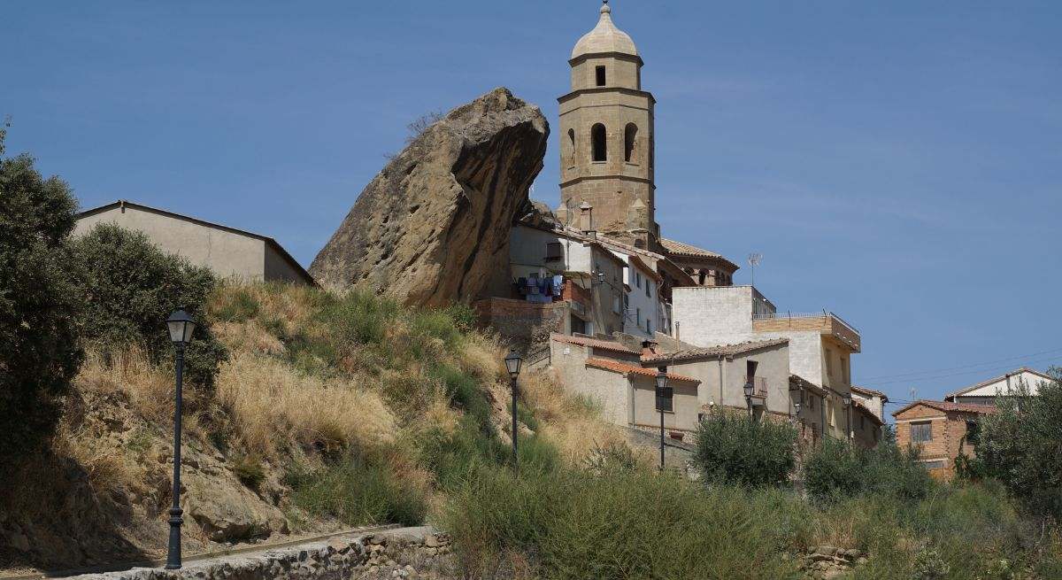 Torre de la iglesia del pueblo al lado de una formación rocosa