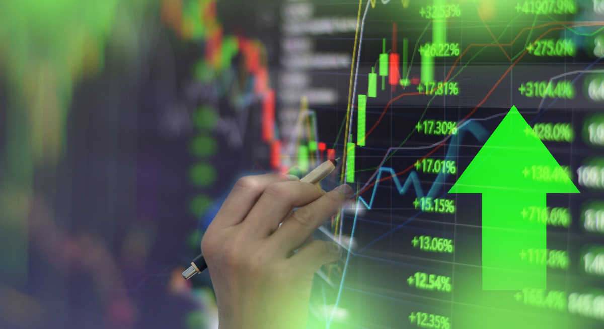 Una mano señalando un gráfico del mercado con una flecha verde