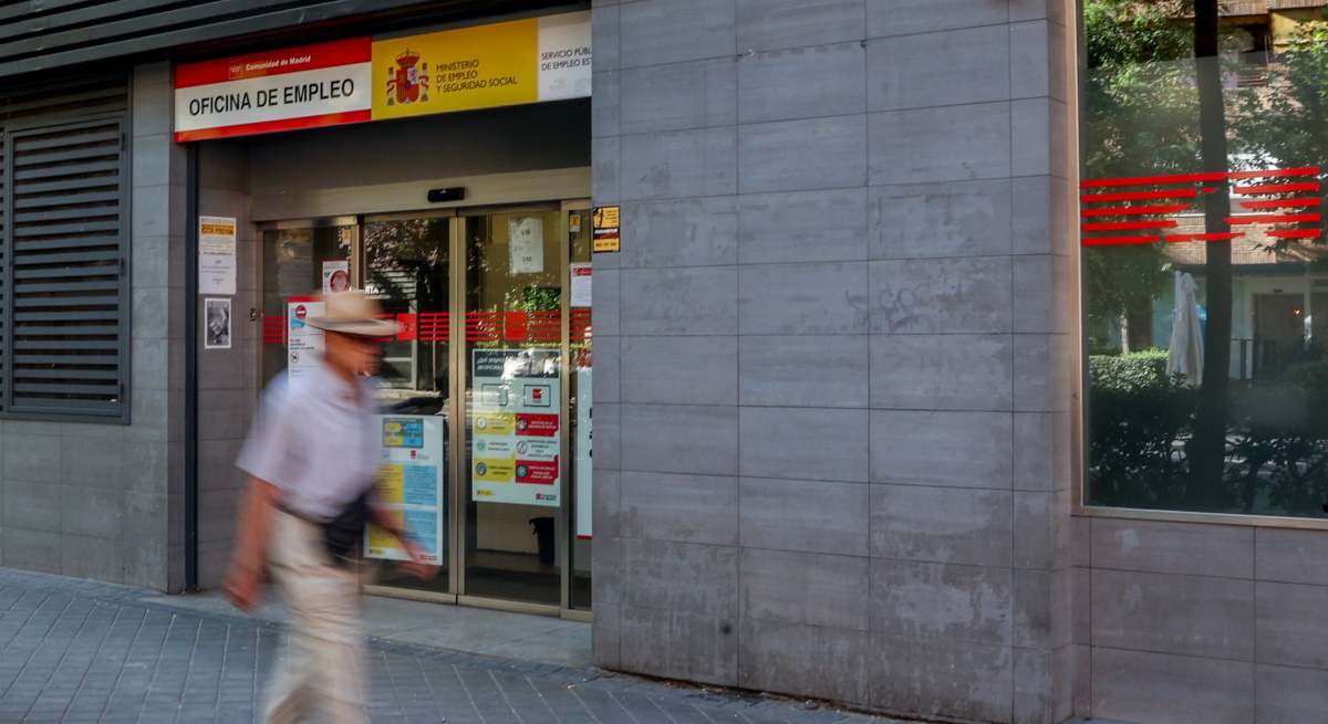 Hombre difuminado pasa por delante de una oficina de empleo