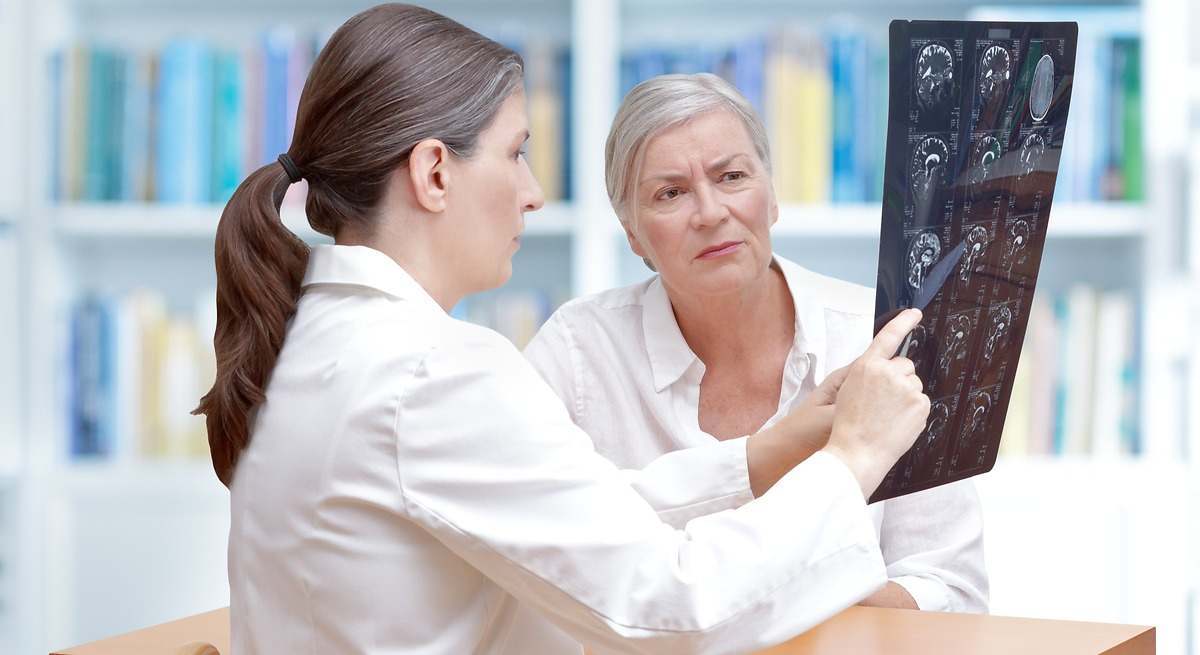 Imagen de una doctora enseñando radiografías a una paciente.