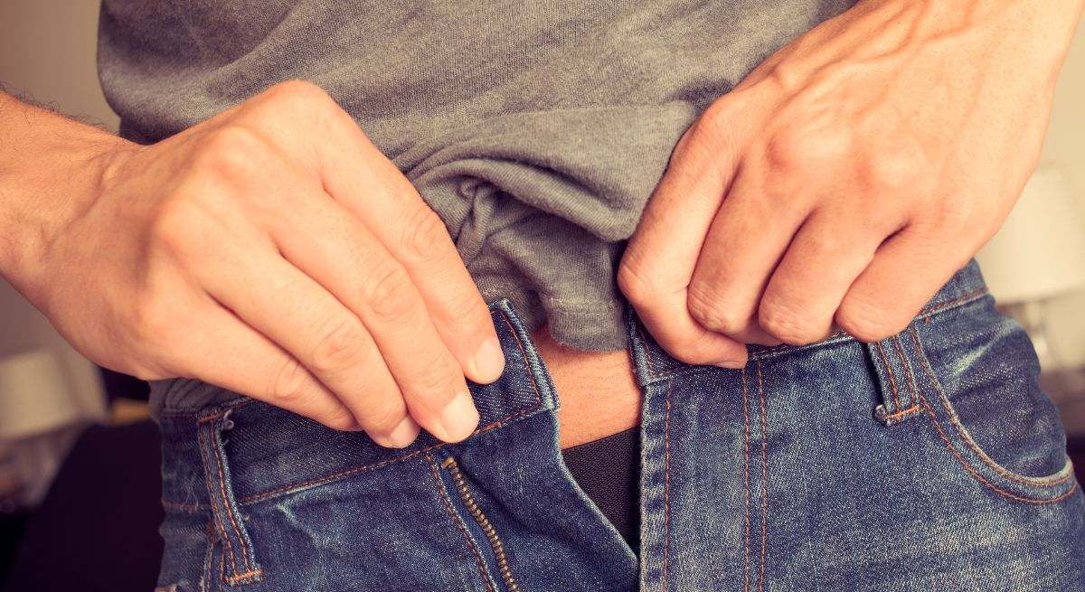 Persona abrochándose el pantalón