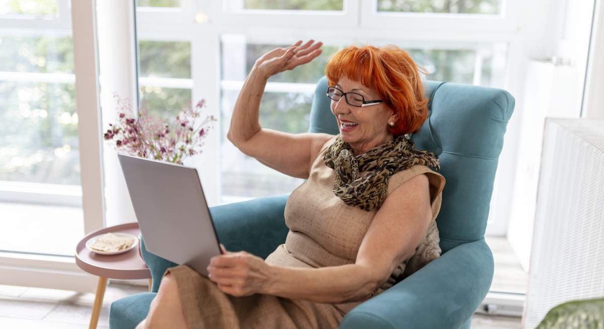 mujer-jubilada-saluda-videollamada-sofa-dreamstime.jpg