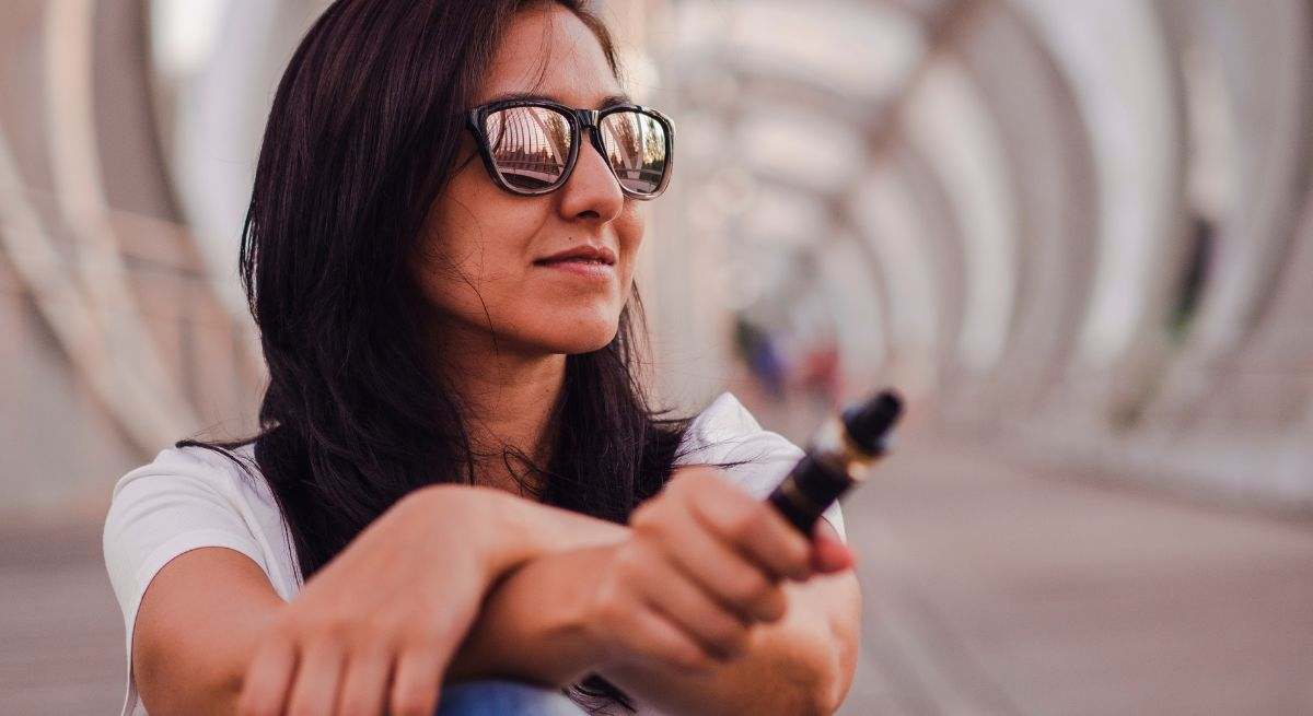 Una mujer usa el vaper cerca de un puente
