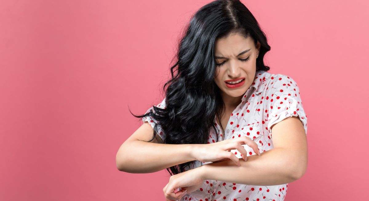 Chica joven se rasca con fuerza el brazo