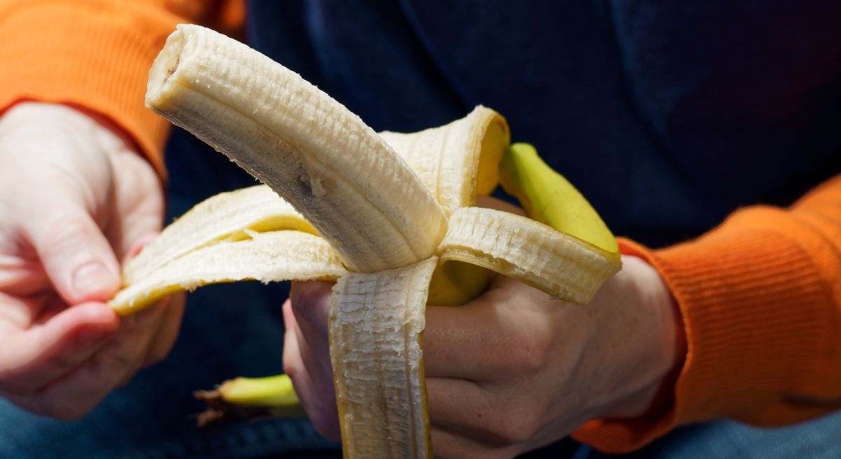 Manos de persona pelando un plátano