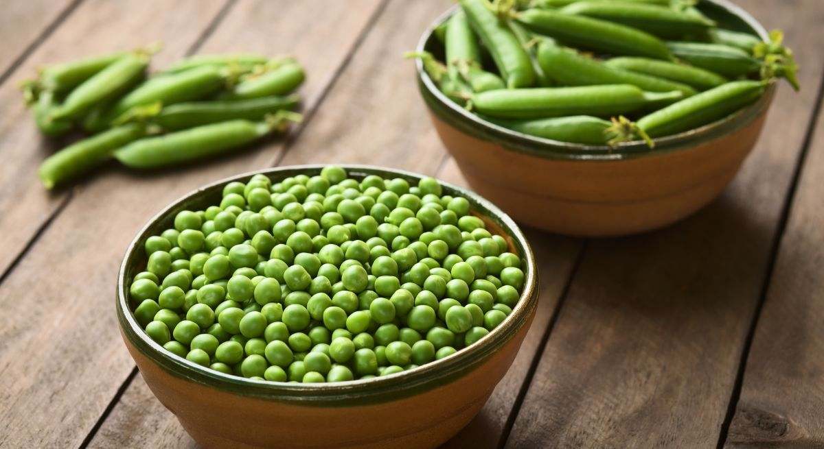 Dos boles con guisantes en vainas y otro con guisantes sueltos