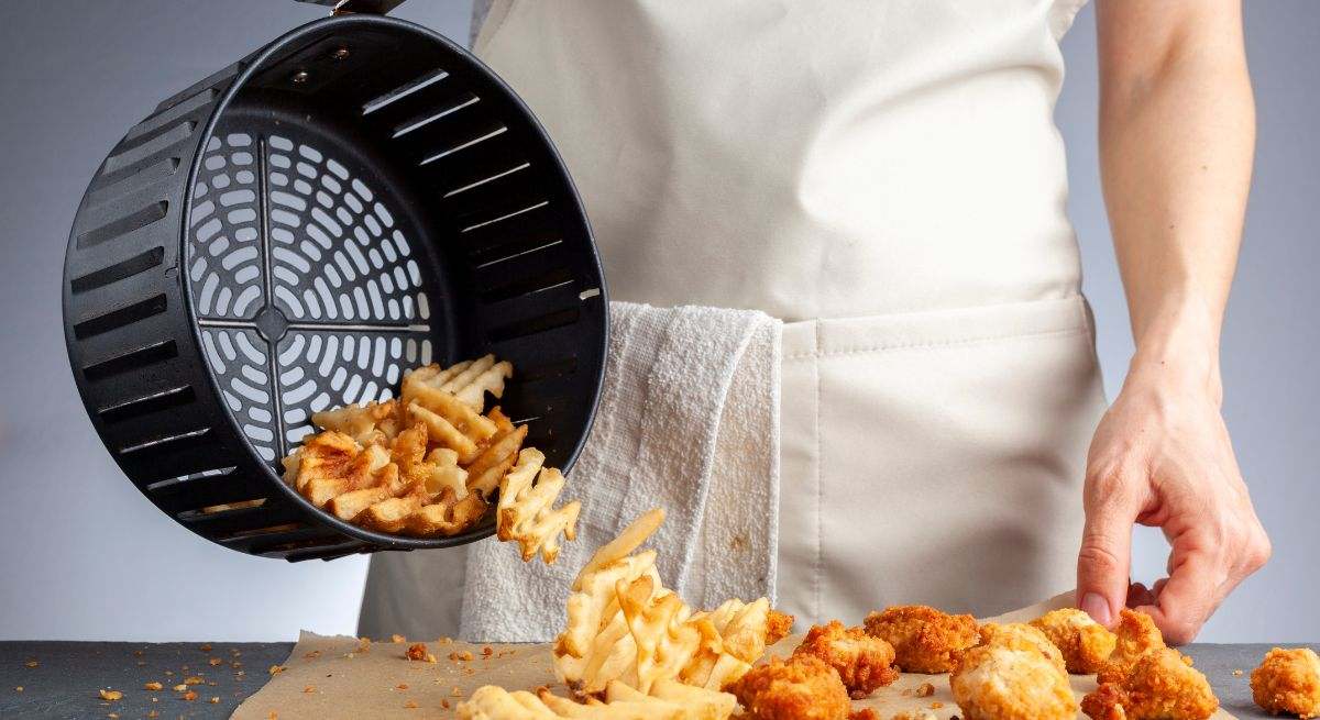 Chef sacando las patatas fritas de la freidora de aire